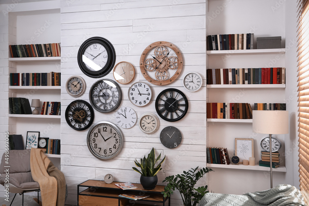 Canvas Prints Stylish room interior with rocking chair, beautiful houseplants and collection of different clocks on white wall