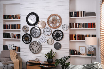 Stylish room interior with rocking chair, beautiful houseplants and collection of different clocks...
