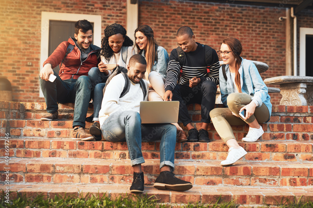 Poster Connecting with like minded young go getters. Shot of a group of students using a laptop together on campus.