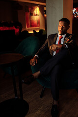 Successful business man sit in a bar, planing new deal or project, smiling. Handsome African...