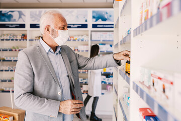 Naklejka na ściany i meble An old man choosing vitamins and supplements during covid 19.