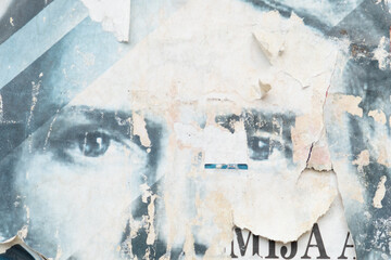 Old and weathered blue street poster with a man eyes background