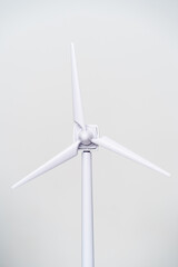 Vertical view of windmill on white background. Front close-up detail of isolated windmill blades with solar energy rotation. Renewable energies and environmental awareness concept.