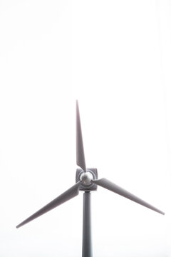 Vertical view of windmill on white background. Front close-up detail of isolated windmill blades with solar energy rotation. Renewable energies and environmental awareness concept.