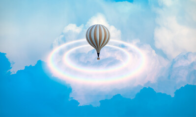 Classic type hot air balloon flying over the clouds with rainbow halo