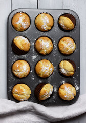Baking tray with baked muffins on wooden white background.