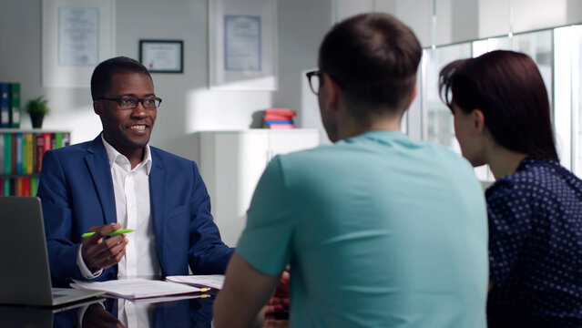 African-American Auto dealer discuss lease terms with customers