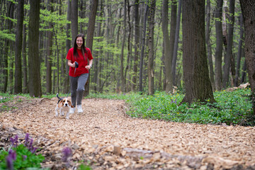 A young girl runs through the woods with her dog
