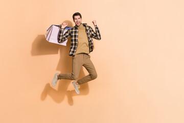 Full length body size view of attractive cheery lucky guy jumping holding bags having fun isolated...