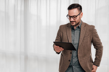 Confident entrepreneur working on business plan over digital tablet at workplace