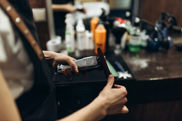 Barber cleaning electric hair clipper at barber shop.