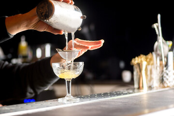 bartender is preparing a cocktail. Bartender pours a cocktail - 498703828