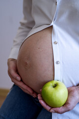 A pregnant woman in a white shirt and blue jeans, holding a ripe green apple in her hands.Pregnancy planning and healthy nutrition of the future mother. Fruits and vitamins in the diet.
a harsh way of