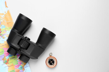 Modern binoculars, compass and world map on white background, flat lay. space for text