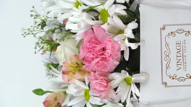 A beautiful composition of delicate flowers in a white gift box on the table on a neutral background. A gift for a holiday, Birthday, wedding, Mother's Day, Valentine's Day, rotation on the turntable.