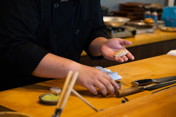 Close-up Professional sushi chef hand preparing sashimi to make perfect sushi with precision and confident.