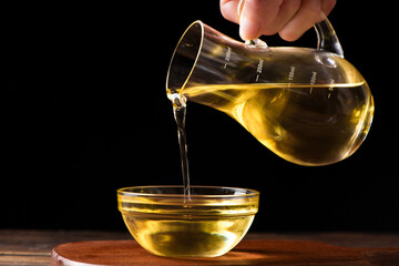 Pouring cooking oil into glass bowl on table