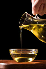 Pouring cooking oil into glass bowl on table