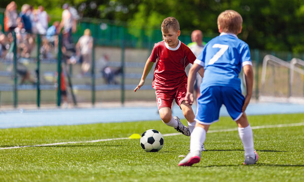 Teenage boy running with soccer ball during tournament game. European football match between school teams. Sporty kids kicking ball