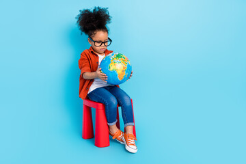 Full body photo of focused concentrated interested little girl studying geography isolated on blue color background