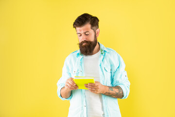 serious bearded man with book on yellow background, education