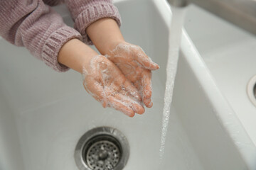Little girl washing hands with liquid soap, closeup