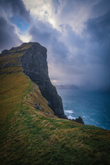 Fototapeta na wymiar Kalsoy Island with Kallur lighthouse on on Faroe islands, Denmark, Europe. Clouds over high cliffs, turquoise Atlantic ocean and spectacular views. November 2021