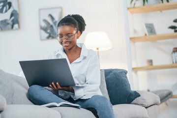 Online connection. Young african american woman in white shirt is at home