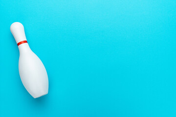 Minimalist photo of bowling pin over turquoise blue background. Flat lay top down image of white bowling pin with copy space.