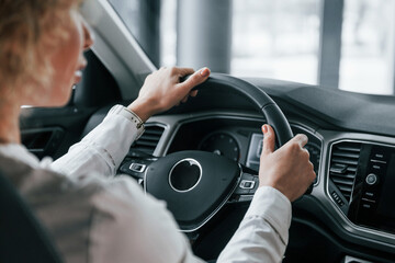 Vehicle interior. Woman with curly blonde hair is in autosalon