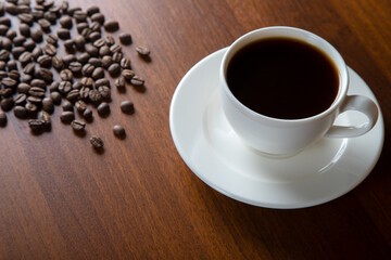 Coffee beans with a cup of coffee on wooden background