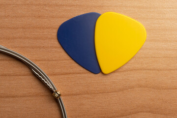 Blue and yellow blank guitar picks on a wooden table