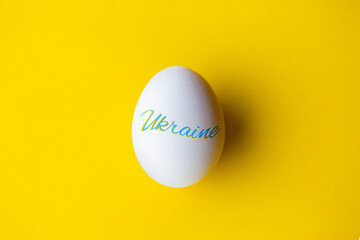 Easter egg with symbols of Ukraine. Patriotic Easter egg. Paska with the flag of Ukraine. Easter egg on a yellow background with the inscription Ukraine. War in Ukraine. Banner with symbols of Ukraine