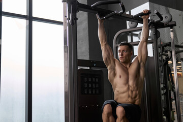 Fototapeta na wymiar Muscular man working out in a gym doing Pull-ups