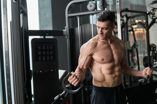 Muscular man working out in gym, strong male torso abs.