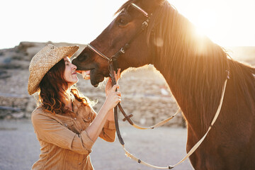 Young farmer woman having tender moment kissing her horse at farm ranch - Focus on face