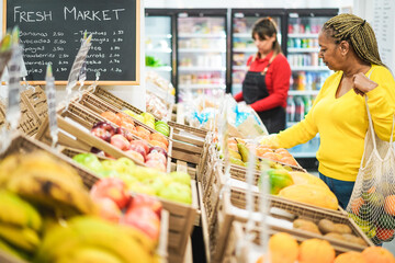 Female customer buying organic food fruits inside eco fresh market - Focus on right african woman hand