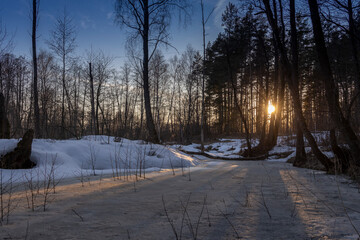 Evening spring landscape, trees by the river, snow and thawed patches. Melting ice and snow.