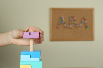 Child playing with toy pyramid indoors, closeup. ABA therapy concept