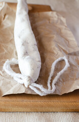 Traditional Catalan thin sausage - fuet. Pork sausage with mold on craft paper. Vertical orientation. Selective focus.