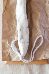 Traditional Catalan thin sausage - fuet. Pork sausage with mold on craft paper. Vertical orientation. Top view.