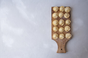 Preparation of dumplings. Arranged dumplings on a cutting board on a gray background for text. 