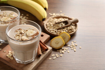 Tasty banana smoothie with oatmeal and cinnamon on wooden table, space for text