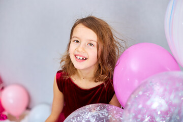 Fototapeta na wymiar Cute, Joyful little girl in pink dress and hat play with balloons at home birthday party