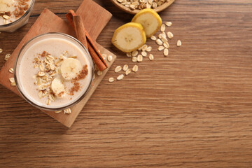 Fototapeta na wymiar Tasty banana smoothie with oatmeal and cinnamon on wooden table, flat lay. Space for text