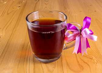 a glass cup of tea and spoon on a light wooden table background