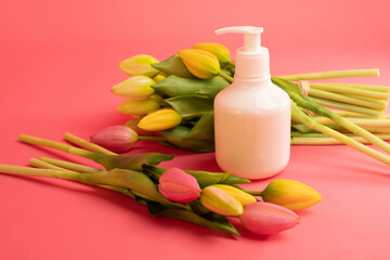 Mockup of beauty cosmetic makeup bottle product with skincare healthcare concept on pink background with tulips.