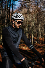 Portrait of cyclist in outfit, wearing helmet and goggles on the forest.