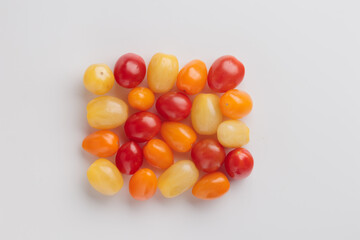 Yellow, orange and red cherry tomatoes on a white background