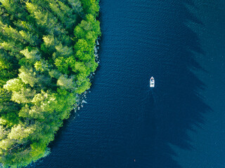 Aerial view of blue lake with fishing boat and green woods in Finland